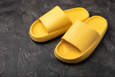 Siyah mermer arka planda ev terlikleri. Kapalı ayakkabılar. Düz çizgi. Rahat etmek için rahat terlikler. Yakın plan. Mesaj için yer. Boşluğu kopyala.