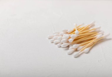 Beyaz çimento arka planında pamuk örnekleri. Bambu pamuk tomurcukları. Kulakların hijyeni için. Çevre dostu materyaller. Hijyenik pamuk tokaları..