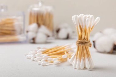 Beyaz çimento arka planında pamuk örnekleri. Bambu pamuk tomurcukları. Kulakların hijyeni için. Çevre dostu materyaller. Hijyenik pamuk tokaları..