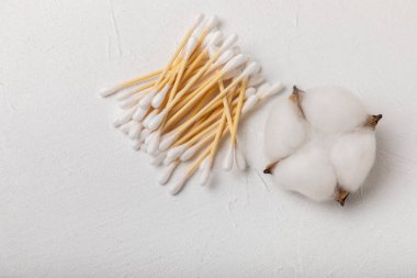 Beyaz çimento arka planında pamuk örnekleri. Bambu pamuk tomurcukları. Kulakların hijyeni için. Çevre dostu materyaller. Hijyenik pamuk tokaları..