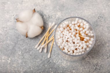 El işi ambalajında pamuk çubukları ve gri çimento arka planında tutucu. Bambu pamuk tomurcukları. Kulakların hijyeni için. Çevre dostu materyaller. Hijyenik pamuk tokaları..