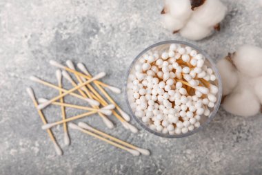 El işi ambalajında pamuk çubukları ve gri çimento arka planında tutucu. Bambu pamuk tomurcukları. Kulakların hijyeni için. Çevre dostu materyaller. Hijyenik pamuk tokaları..