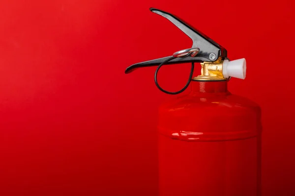 Fire extinguisher on a red background with place for text. Close-up. Fire extinguisher on the wall. Fire safety system. Security concept. Place for text. Copy space.