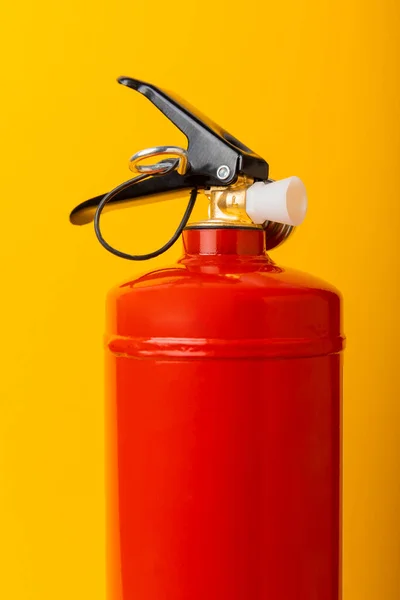 Fire extinguisher on a yellow background with place for text. Close-up. Fire extinguisher on the wall. Fire safety system. Security concept. Place for text. Copy space.