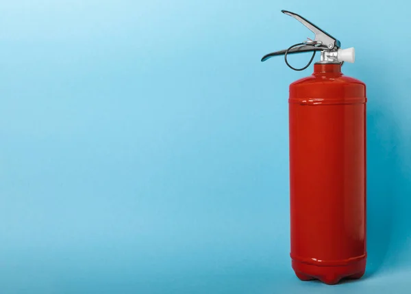 Fire extinguisher on a blue background with place for text. Close-up. Fire extinguisher on the wall. Fire safety system. Security concept. Place for text. Copy space.