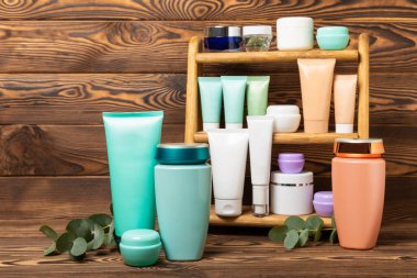 Care cosmetics for face, body and hair on a wooden shelf. A set of cosmetic products shampoo, cream, serum and scrub on a shelf in the bathroom. Foreground. copy space. Beauty concept.