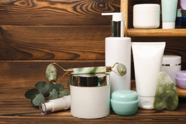 Care cosmetics for face, body and hair on a wooden shelf. A set of cosmetic products shampoo, cream, serum and scrub on a shelf in the bathroom. Foreground. copy space. Beauty concept.