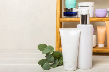 Banyodaki ahşap bir rafta yüz, vücut ve saç bakımı için makyaj malzemeleri. Kozmetik ürünleri, şampuan, krem, serum ve banyodaki bir rafa fırça. Ön planda. kopyalama alanı. Güzellik konsepti.