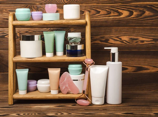 Care cosmetics for face, body and hair on a wooden shelf. A set of cosmetic products shampoo, cream, serum and scrub on a shelf in the bathroom. Foreground. copy space. Beauty concept.