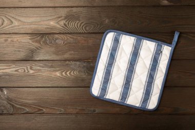 Kahverengi ahşap arka planda tutucu. Masada koruyucu fırın eldiveni. Mutfak eşyaları. Mutfak aksesuarları. Yakın plan. Metin için yeri olan üst görünüm.