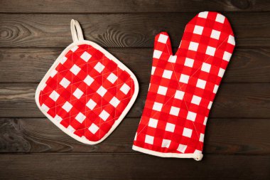 Tutucu ve Mutfak Mitten kahverengi ahşap arka planda. Masanın üstünde koruyucu fırın eldivenleri. Mutfak eşyaları. Mutfak aksesuarları. Yakın plan. Metin için yeri olan üst görünüm.