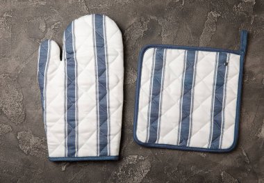 Potholder ve Kitchen Mitten siyah mermer arka planda. Masada koruyucu fırın eldiveni var. Mutfak eşyaları. Mutfak aksesuarları. Yakın plan. Metin için yeri olan üst görünüm.