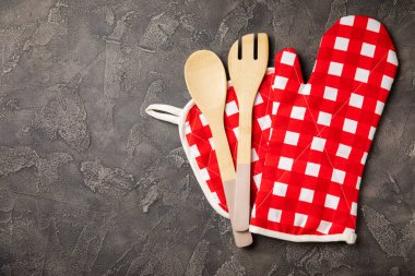 Ahşap mutfak aletleri, kesim tahtası, tutacağı ve eldiven masanın üstünde. Mutfak eldiveni ve koruyucu fırın eldivenleri masanın üstünde. Mutfak eşyaları. Mutfak aksesuarları. Yakın çekim. Üst manzara..