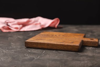 Ahşap mutfak masasında havlunun üzerinde tahta kesme tahtası. Siyah desenli arka planda kesme tahtası ve mutfak havlusu. Menü yemek kartı ya da yemek tarifleri arka plan kavramı. MOCKUP Tasarım. Metin için yer, kopyalama alanı.