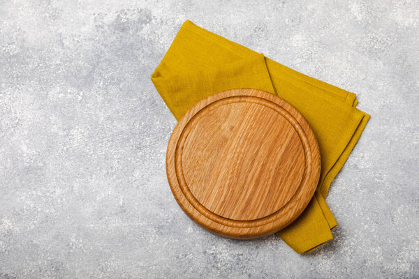 Cutting board over towel on wooden kitchen table. Pizza board and kitchen towel on textured background. Menu food card or recipes background concept.MOCKUP. Design. Place for text, copy space.