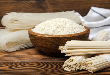 Koyu kahverengi ahşap üzerinde pirinç unlu erişte. Funchoza. Kuru pirinç eriştesi. Yakın çekim. Uzayı kopyala. Metin için yer.