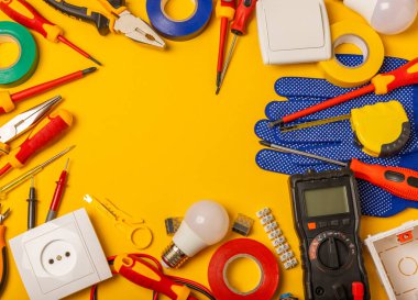 Sarı zemin üzerindeki elektrik teçhizatı kopya alanı ile üst görünüm. Elektrik aracı seti. Çoklu metre, testçi, tornavida, kesiciler, koli bandı, lamba, mezura, mezura ve kablo..