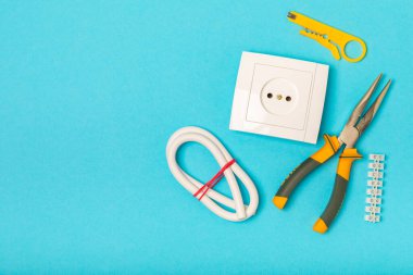 Mavi arka planda kopyalanmış elektrik teçhizatı. Üst görünüm. Elektrik aracı seti. Çoklu metre, test cihazı, tornavida, kesici, koli bandı, lamba, mezura, mezura ve kablo..