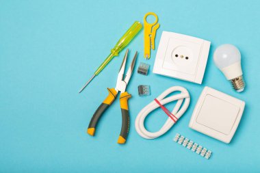 Mavi arka planda kopyalanmış elektrik teçhizatı. Üst görünüm. Elektrik aracı seti. Çoklu metre, test cihazı, tornavida, kesici, koli bandı, lamba, mezura, mezura ve kablo..