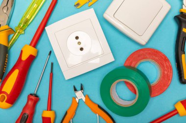 Mavi arka planda kopyalanmış elektrik teçhizatı. Üst görünüm. Elektrik aracı seti. Çoklu metre, test cihazı, tornavida, kesici, koli bandı, lamba, mezura, mezura ve kablo..