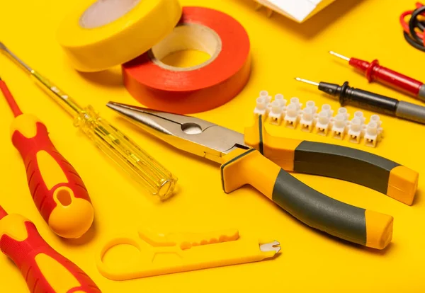 Sarı zemin üzerindeki elektrik teçhizatı kopya alanı ile üst görünüm. Elektrik aracı seti. Çoklu metre, testçi, tornavida, kesiciler, koli bandı, lamba, mezura, mezura ve kablo..