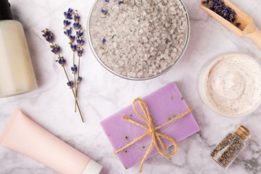 Lavanta spreyi, deniz tuzu, lavanta çiçekleri, aroma mumu, vücut kremi ve el yapımı sabun. Mermer arka planda lavanta çiçekleri olan doğal bitkisel kozmetik ürünleri. Rahatlayın. Güzellik tedavileri..