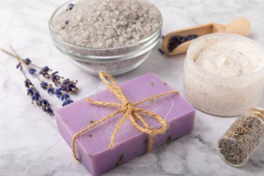 Lavender spa.Sea salt,lavender flowers,aroma candle,body cream and handmade soap.Natural herbal cosmetics with lavender flowers on marble background.Relax concept.Beauty treatments.Copy space.