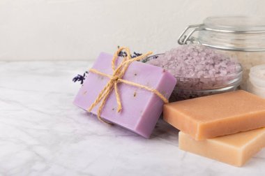 Lavender spa.Sea salt,lavender flowers,aroma candle,body cream and handmade soap.Natural herbal cosmetics with lavender flowers on marble background.Relax concept.Beauty treatments.Copy space.