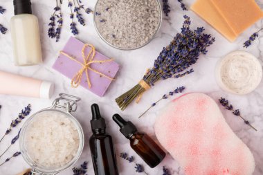 Lavanta spreyi, deniz tuzu, lavanta çiçekleri, aroma mumu, vücut kremi ve el yapımı sabun. Mermer arka planda lavanta çiçekleri olan doğal bitkisel kozmetik ürünleri. Rahatlayın. Güzellik tedavileri..