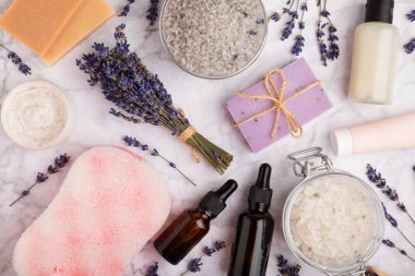 Lavanta spreyi, deniz tuzu, lavanta çiçekleri, aroma mumu, vücut kremi ve el yapımı sabun. Mermer arka planda lavanta çiçekleri olan doğal bitkisel kozmetik ürünleri. Rahatlayın. Güzellik tedavileri..