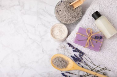 Lavender spa.Sea salt,lavender flowers,aroma candle,body cream and handmade soap.Natural herbal cosmetics with lavender flowers on marble background.Relax concept.Beauty treatments.Copy space.