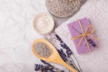 Lavender spa.Sea salt,lavender flowers,aroma candle,body cream and handmade soap.Natural herbal cosmetics with lavender flowers on marble background.Relax concept.Beauty treatments.Copy space.