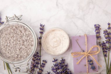 Lavanta spreyi, deniz tuzu, lavanta çiçekleri, aroma mumu, vücut kremi ve el yapımı sabun. Mermer arka planda lavanta çiçekleri olan doğal bitkisel kozmetik ürünleri. Rahatlayın. Güzellik tedavileri..