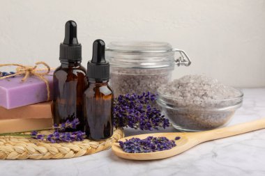 Lavanta spreyi, deniz tuzu, lavanta çiçekleri, aroma mumu, vücut kremi ve el yapımı sabun. Mermer arka planda lavanta çiçekleri olan doğal bitkisel kozmetik ürünleri. Rahatlayın. Güzellik tedavileri..