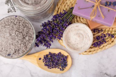 Lavender spa.Sea salt,lavender flowers,aroma candle,body cream and handmade soap.Natural herbal cosmetics with lavender flowers on marble background.Relax concept.Beauty treatments.Copy space.