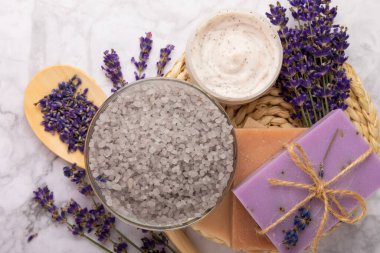 Lavanta spreyi, deniz tuzu, lavanta çiçekleri, aroma mumu, vücut kremi ve el yapımı sabun. Mermer arka planda lavanta çiçekleri olan doğal bitkisel kozmetik ürünleri. Rahatlayın. Güzellik tedavileri..