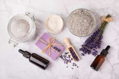 Lavanta spreyi, deniz tuzu, lavanta çiçekleri, aroma mumu, vücut kremi ve el yapımı sabun. Mermer arka planda lavanta çiçekleri olan doğal bitkisel kozmetik ürünleri. Rahatlayın. Güzellik tedavileri..