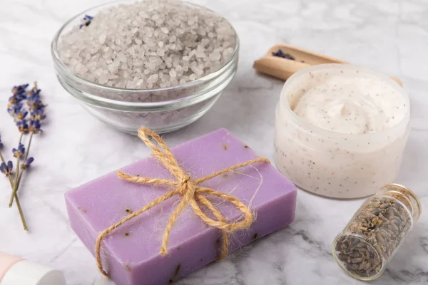 Lavender spa.Sea salt,lavender flowers,aroma candle,body cream and handmade soap.Natural herbal cosmetics with lavender flowers on marble background.Relax concept.Beauty treatments.Copy space.
