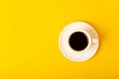 Sarı arka planda bir fincan espresso kahve aroması. Günaydın konsepti. Metnin için fotokopi alanı olan üst görünüm. İyi günler..