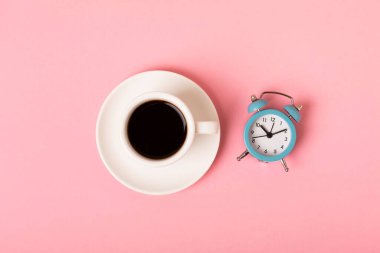 Pembe arka planda bir fincan espresso kahve aroması ve çalar saat. Günaydın konsepti. Metnin için fotokopi alanı olan üst görünüm. İyi günler..