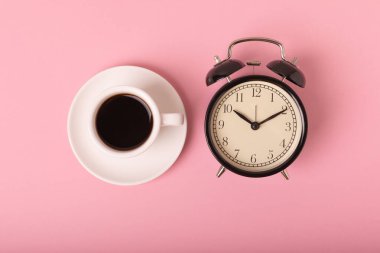 Pembe arka planda bir fincan espresso kahve aroması ve çalar saat. Günaydın konsepti. Metnin için fotokopi alanı olan üst görünüm. İyi günler..