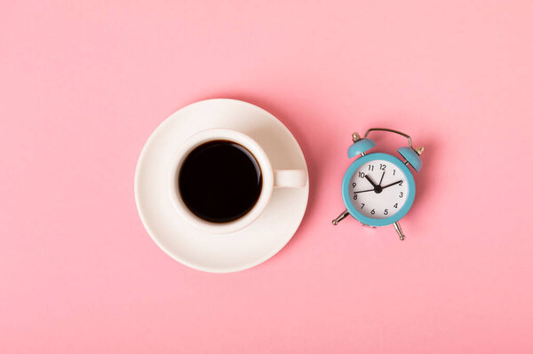 Cup of espresso coffee aroma and alarm clock on a pink background. Good morning concept. Top view with copy space for your text.Have a nice day.