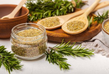 Kasede kurutulmuş biberiye ve beyaz ahşap arka planda taze biberiye dalları. Et ve balık pişirmek için baharatlı baharatlar. Yemek tarifi. Taze biberiye. Metin için yer, kopyalamak için yer.