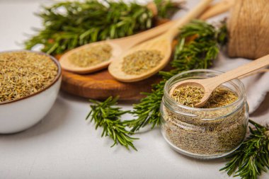 Kasede kurutulmuş biberiye ve beyaz ahşap arka planda taze biberiye dalları. Et ve balık pişirmek için baharatlı baharatlar. Yemek tarifi. Taze biberiye. Metin için yer, kopyalamak için yer.