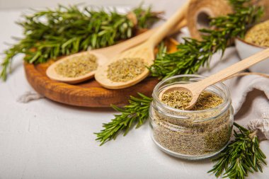 Kasede kurutulmuş biberiye ve beyaz ahşap arka planda taze biberiye dalları. Et ve balık pişirmek için baharatlı baharatlar. Yemek tarifi. Taze biberiye. Metin için yer, kopyalamak için yer.