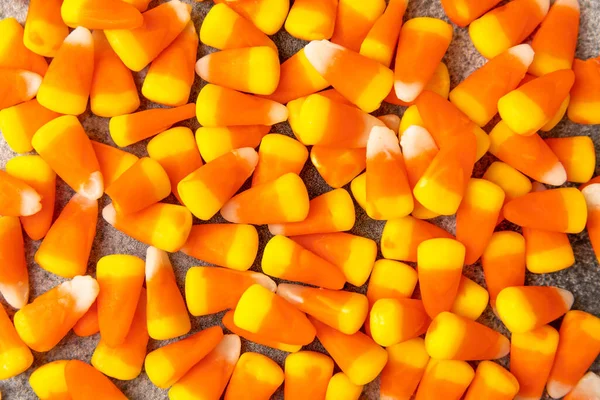 Halloween candy corn with pumpkin flavor and dragees on a black background. Classic sweet Halloween treats. Halloween holiday concept and Jack lantern.Place for text. Place to copy.