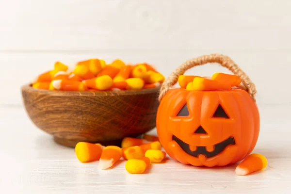 Halloween candy corn with pumpkin flavor, jelly eye on a white background. Classic sweet Halloween candy treats. Halloween holiday concept with candy corn and jack o lantern.