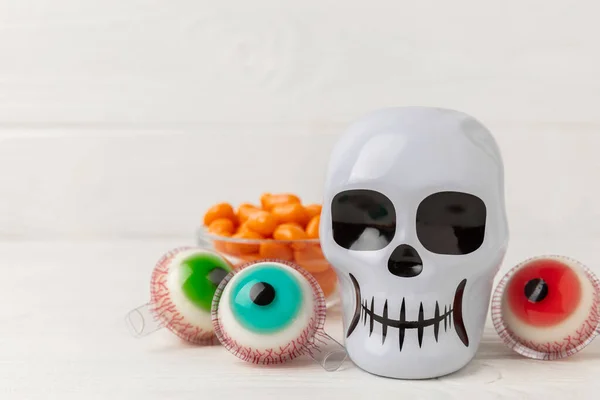 Halloween gummy eye candy and sugar skull on white background. Classic sweet Halloween candy treats. Halloween holiday concept with candy corn and jack o lantern.