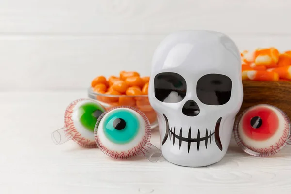 Halloween gummy eye candy and sugar skull on white background. Classic sweet Halloween candy treats. Halloween holiday concept with candy corn and jack o lantern.