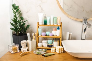 Banyodaki rafta makyaj malzemeleri var. Kozmetik tüpü. Temizleyici, yüz ve vücut kremi yüz silindiri ve gua sha, tonik. Tuvaletin içinde kozmetik ürünleri olan raflar. Güzellik konsepti..